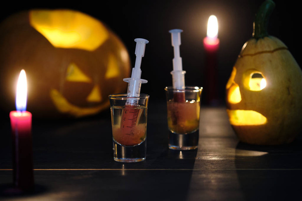 Halloween sangriento cóctel Mary y dos siniestras linternas jack en una mesa de madera oscura
. - Foto, imagen