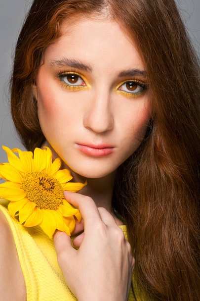 Woman with stylish colorful makeup and sunflowers - Фото, зображення