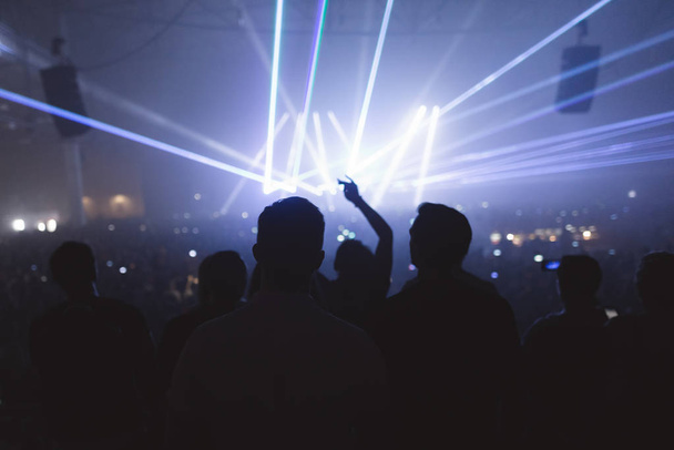 der berühmte DJ gibt ein Konzert. Silhouetten von Fans beim Konzert. lebendige Atmosphäre des Auftritts des Musikers. - Foto, Bild