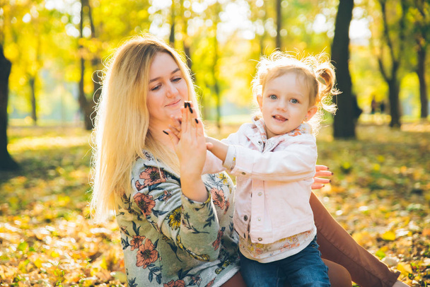 mather com a filha pequena do toddle que joga no parque público da cidade do outono - Foto, Imagem