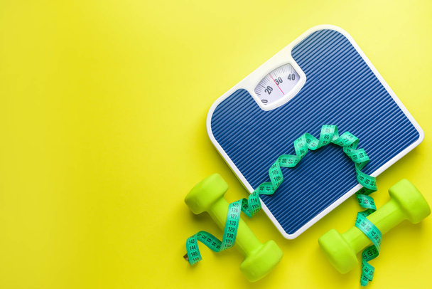 Waagen, Kurzhanteln und Maßband auf farbigem Hintergrund. Gewichtsverlust-Konzept - Foto, Bild