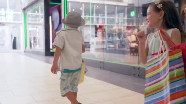 μαύρη Παρασκευή, χαρούμενα παιδιά με τσάντες στο χέρι είναι ευχαριστημένοι με τις νέες αγορές στο εμπορικό κέντρο - Πλάνα, βίντεο