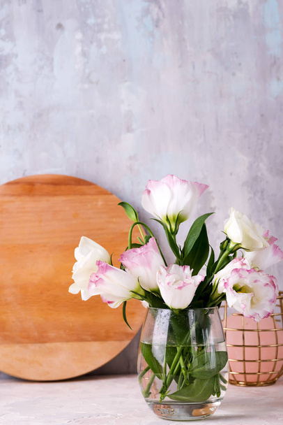 Eustoma flores en jarrón en la mesa cerca de la pared de piedra, espacio para el texto. En blanco para postales
 - Foto, imagen
