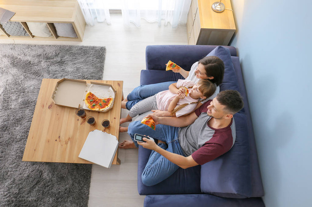 Happy family eating pizza while watching TV at home - Photo, Image