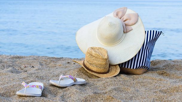 strandmuts, strandtas, zonnebril op het zand van een strand tegen de blauwe zee. Vakantie, rust. - Foto, afbeelding