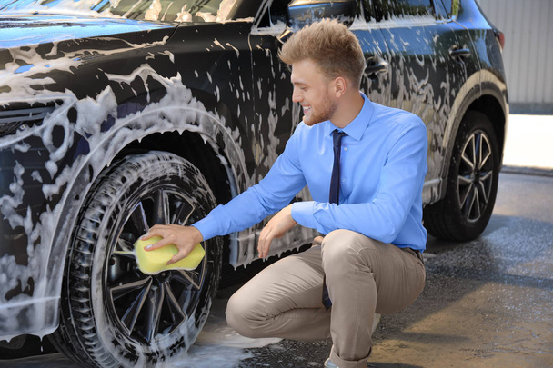 Businessman cleaning auto with sponge at self-service car wash - Fotó, kép