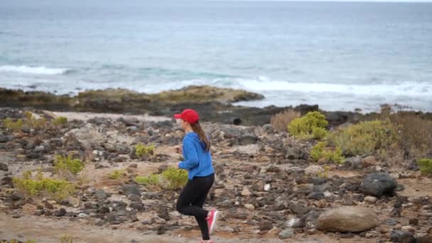 Woman runs along the stony shore of the ocean. Healthy active lifestyle. Slow motion - Footage, Video