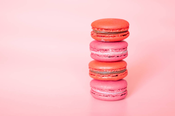 Pink macaroons in a stack on a fashionable coral background - 写真・画像