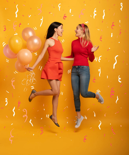 Girls ready for a party with balloons. Joyful an happiness expression. Yellow background - Foto, imagen