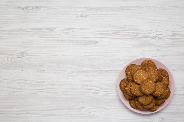 Biscuits aux céréales sur une assiette rose sur une surface en bois blanc, dessus vi
 - Photo, image