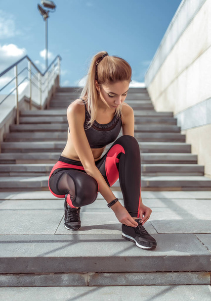 Girl athlete, sports woman tying shoelaces on shoe slippers, jogging training summer autumn spring in city, sportswear, top leggings, sneakers, active fitness lifestyle, outdoor sports exercise. - Foto, Bild