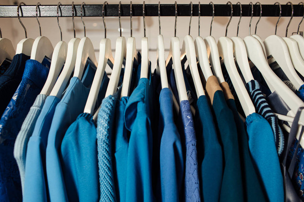 Close-up zicht op verschillende stijlvolle kleding opknoping op hangers in de boetiek. Kleding - Foto, afbeelding