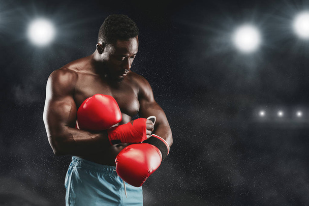 Professional boxer staying on boxing ring, wearing red gloves - Fotó, kép