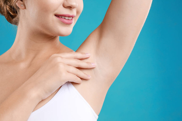 Young woman with smooth clean armpit on teal background, closeup. Using deodorant - Fotografie, Obrázek