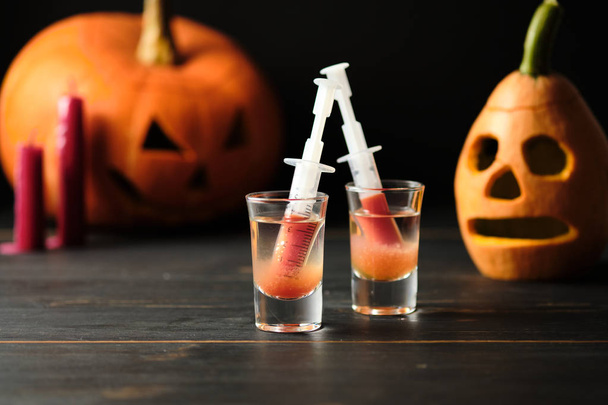 Halloween sangriento cóctel Mary y dos siniestras linternas jack en una mesa de madera oscura
. - Foto, imagen