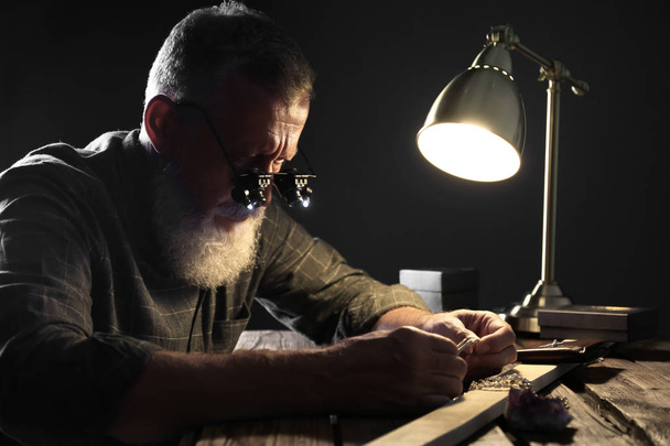Male jeweler evaluating diamond ring in workshop - Fotoğraf, Görsel