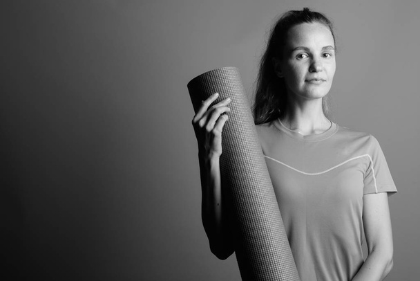 Молодая красивая женщина держит коврик для тренировки йоги
 - Фото, изображение