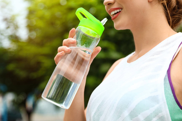 Young woman drinking water outdoors, closeup. Refreshing drink - Photo, image