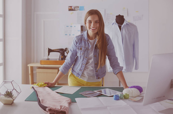 Beautiful fashion designer standing near desk in studio - Foto, Imagem