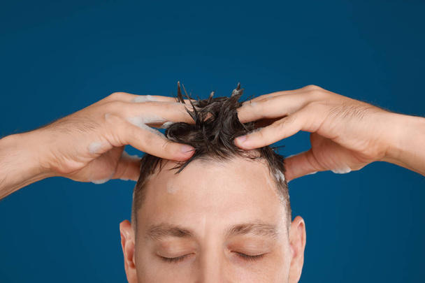 Man washing hair on blue background, closeup - Foto, Bild