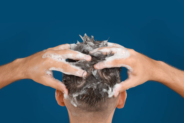 Άνδρας που πλένει τα μαλλιά σε μπλε φόντο, κοντινό πλάνο - Φωτογραφία, εικόνα