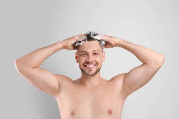 Handsome man washing hair on white background - Fotografie, Obrázek