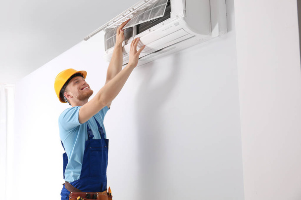 Professional technician maintaining modern air conditioner indoors - Foto, immagini