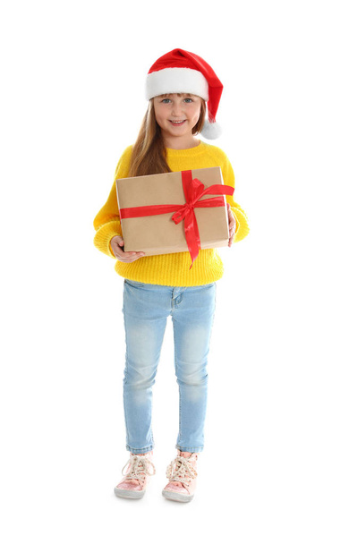 niedliches kleines Mädchen mit Weihnachtsmütze und Weihnachtsgeschenk auf weißem Hintergrund - Foto, Bild