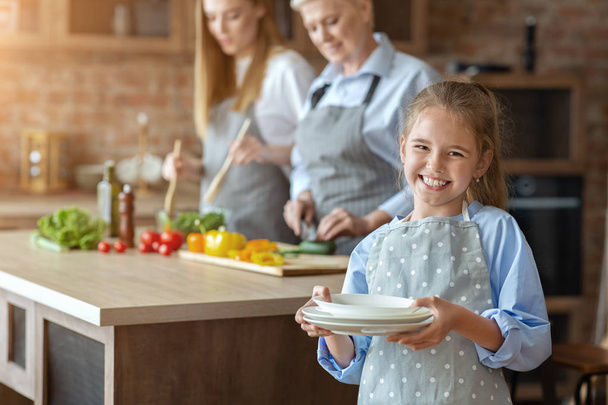 Little girtl helping mother and granny to set the table - Foto, afbeelding
