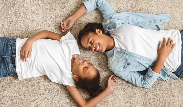 Twee mooie zusters leggen op de vloer van aangezicht tot aangezicht - Foto, afbeelding
