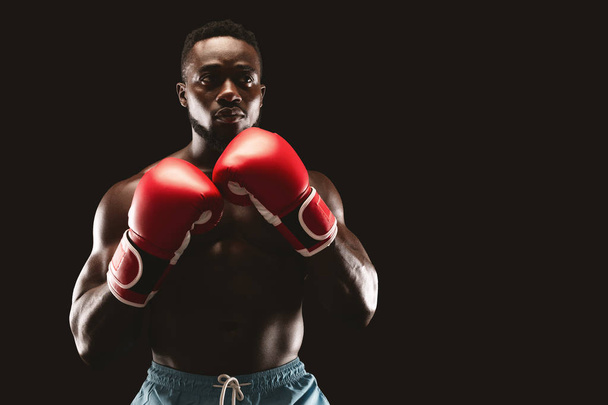African guy posing in boxing stance over black background - Photo, Image