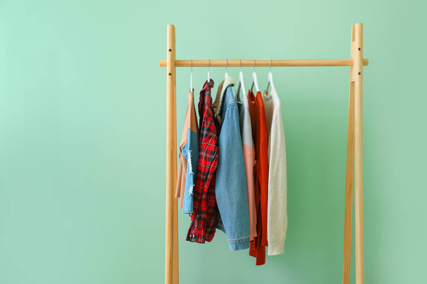 Rack with hanging clothes on color background - Фото, изображение