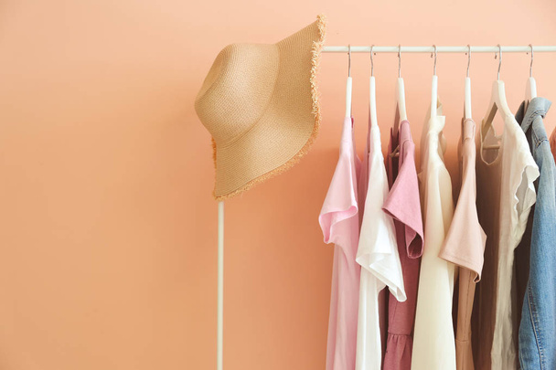 Rack with hanging clothes on color background - Foto, Imagen