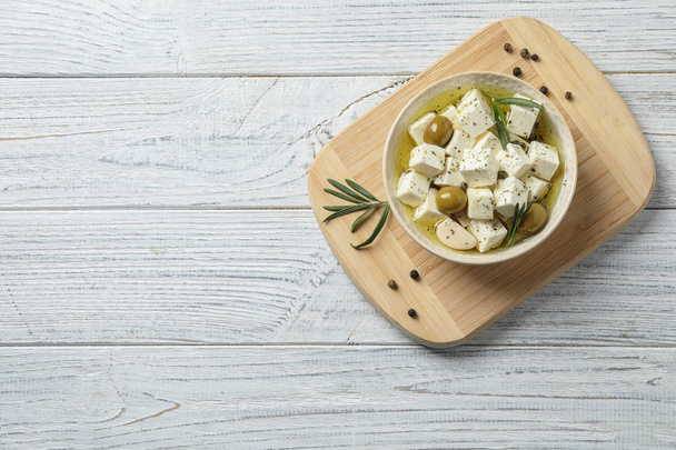 Flat lay composition with pickled feta cheese in bowl on white wooden table, space for text - Photo, Image