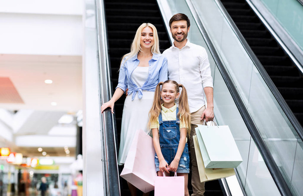 Γονείς και κόρη εκμετάλλευση τσάντες ψώνια χρησιμοποιώντας Escalator στο εμπορικό κέντρο - Φωτογραφία, εικόνα