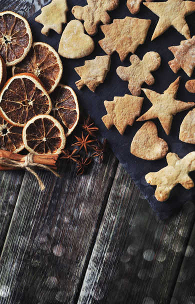 Χριστουγεννιάτικα μπισκότα, κανέλα, αποξηραμένα πορτοκάλια σε ξύλινο φόντο. - Φωτογραφία, εικόνα