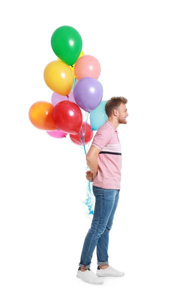 Young man holding bunch of colorful balloons on white background - Foto, imagen