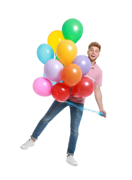 Emotional young man holding bunch of colorful balloons on white background - Photo, Image