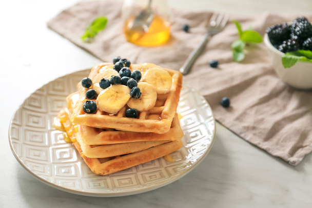 Plate with tasty waffles, fruit and berries on table - Φωτογραφία, εικόνα