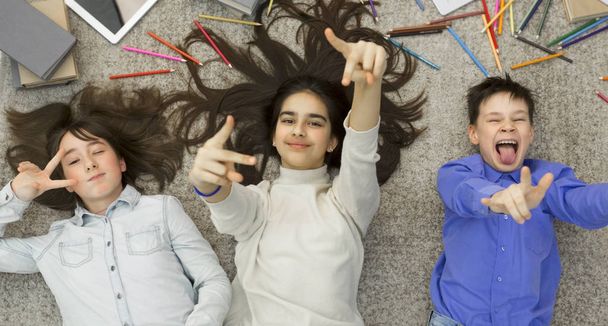 Радісні діти обманюють, лежать на килимі і розважаються
 - Фото, зображення