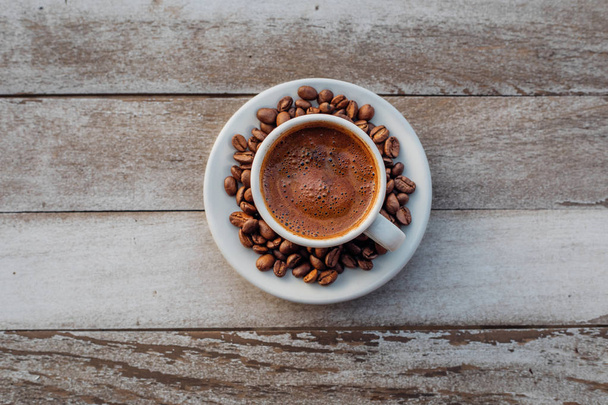 Török vagy görög forró kávé a fehér rusztikus fa asztalon kiömlött kávébabbal. Ez a hagyományos ízletes frissítő görög vagy török kávé a görög vagy török konyha kultúrájából. - Fotó, kép