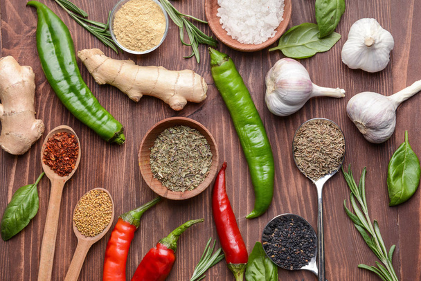 Different dry herbs and spices on wooden background - Photo, image