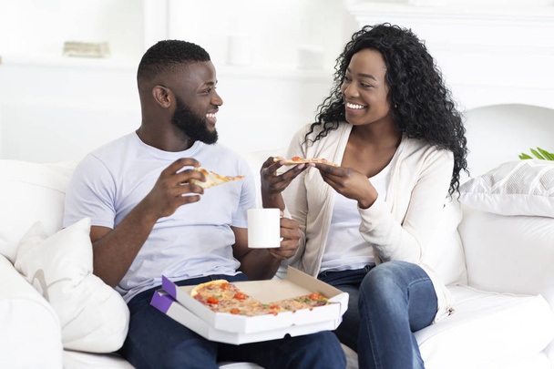 Happy millennial couple eating pizza and drinking coffee at home - Photo, Image