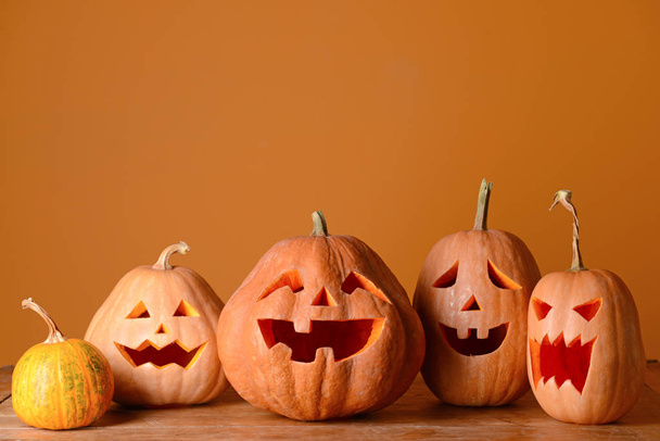 Halloween pumpkins on wooden table against color background - Valokuva, kuva