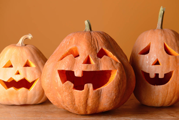 Halloween pumpkins on wooden table against color background - Foto, Bild