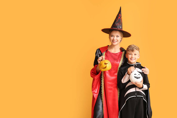 Мать с маленьким сыном в костюмах на Хэллоуин и с тыквами на цветном фоне
 - Фото, изображение