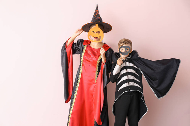 Mutter mit kleinem Sohn in Halloween-Kostümen auf farbigem Hintergrund - Foto, Bild