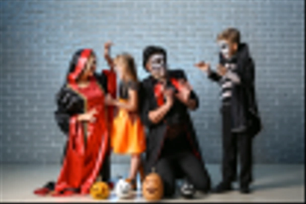 Family in Halloween costumes and with pumpkins on brick background - Photo, Image