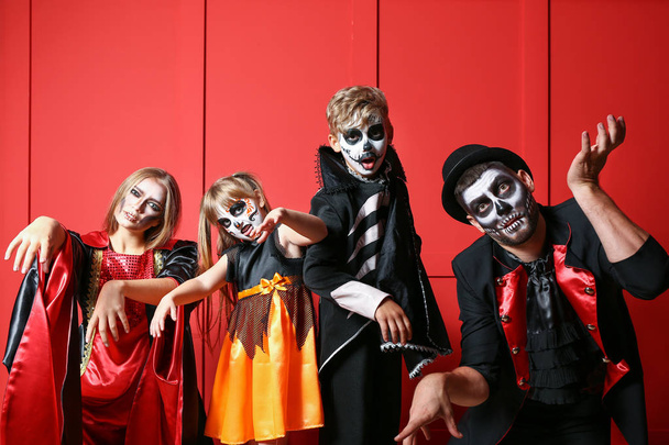 Family in Halloween costumes on color background - 写真・画像