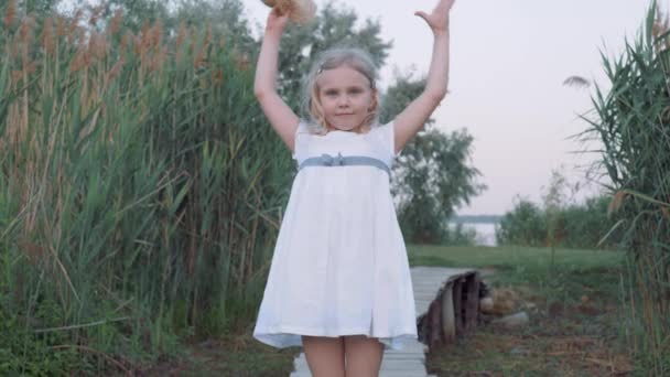 портрет маленької милої дівчинки з блакитними очима в солом'яному капелюсі та білій сукні в природі серед високого очерету
 - Кадри, відео